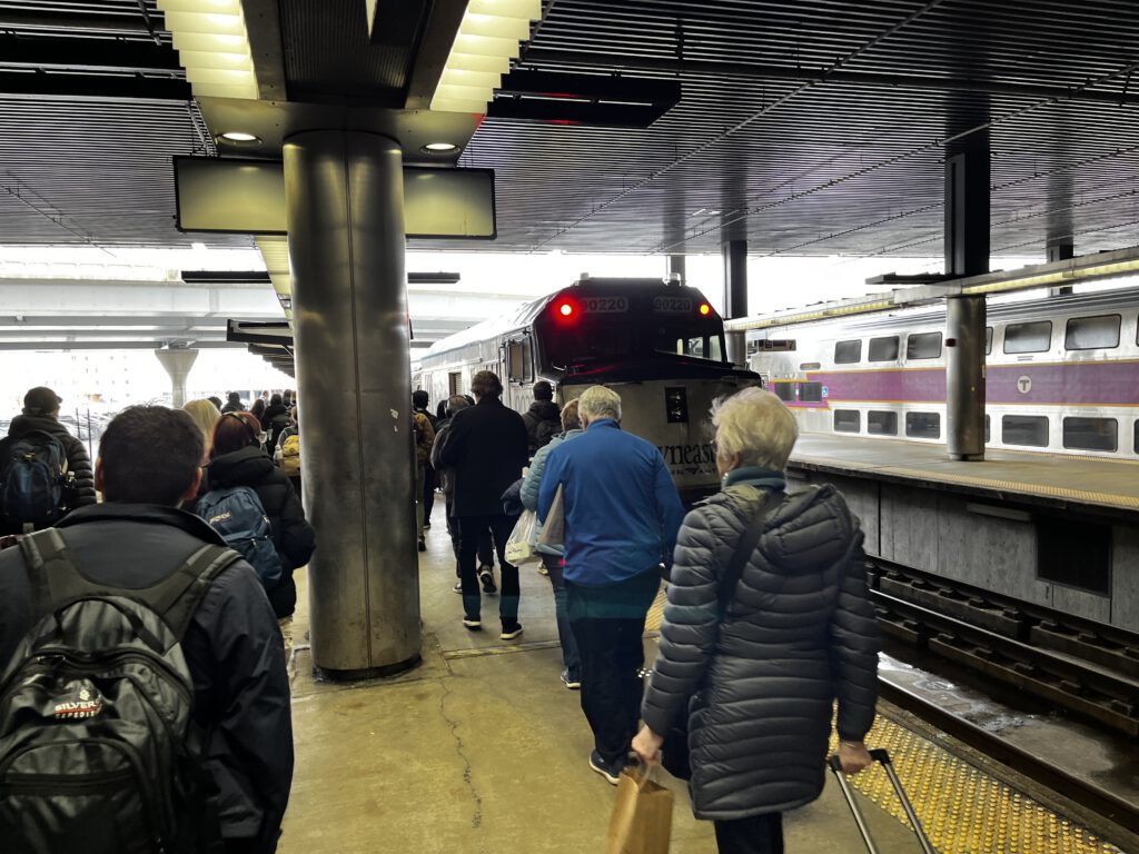 Passengers boarding the Amtrak Downeaster train at a busy station platform