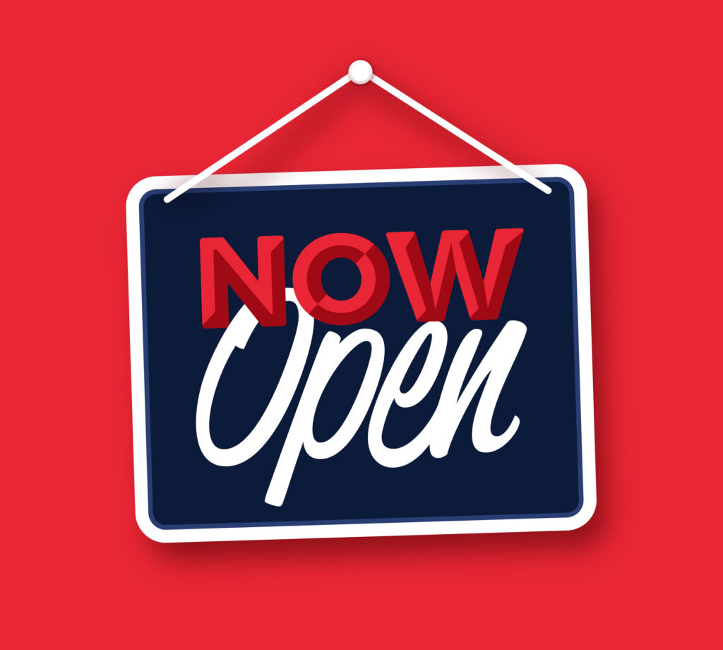 Red and navy sign reading ‘Now Open,’ symbolizing the launch and growth of MarcB IT