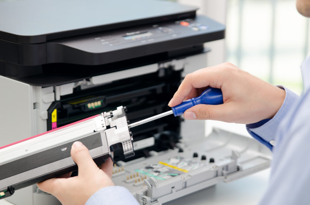 Technician using a screwdriver to service a color laser printer’s toner drum
