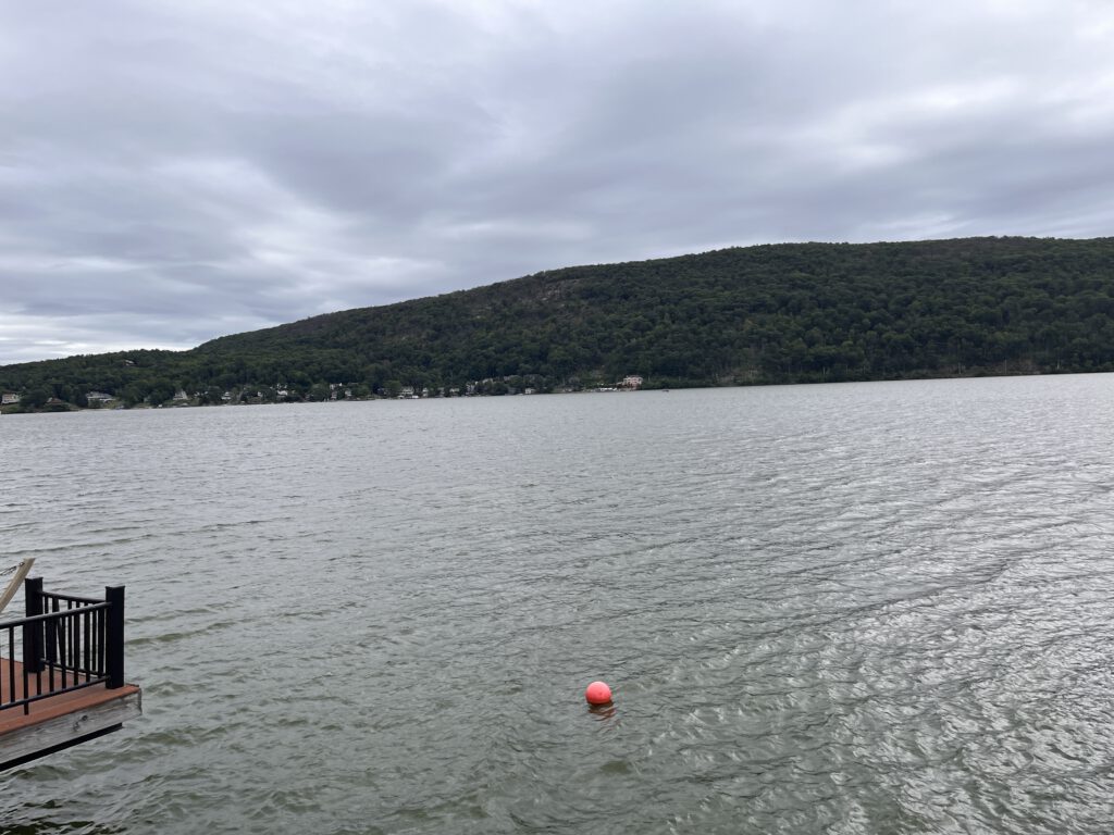 View of Greenwood Lake, NY on a cloudy day with dock and buoy in the foreground