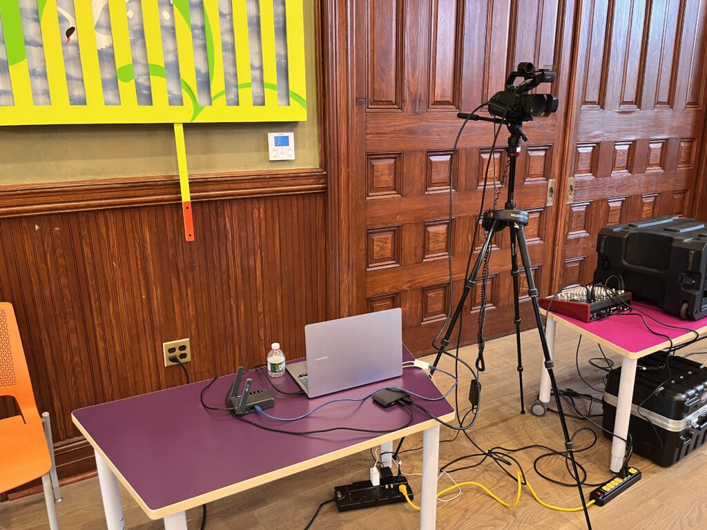 Live streaming setup with camera, laptop, and audio equipment for a public event